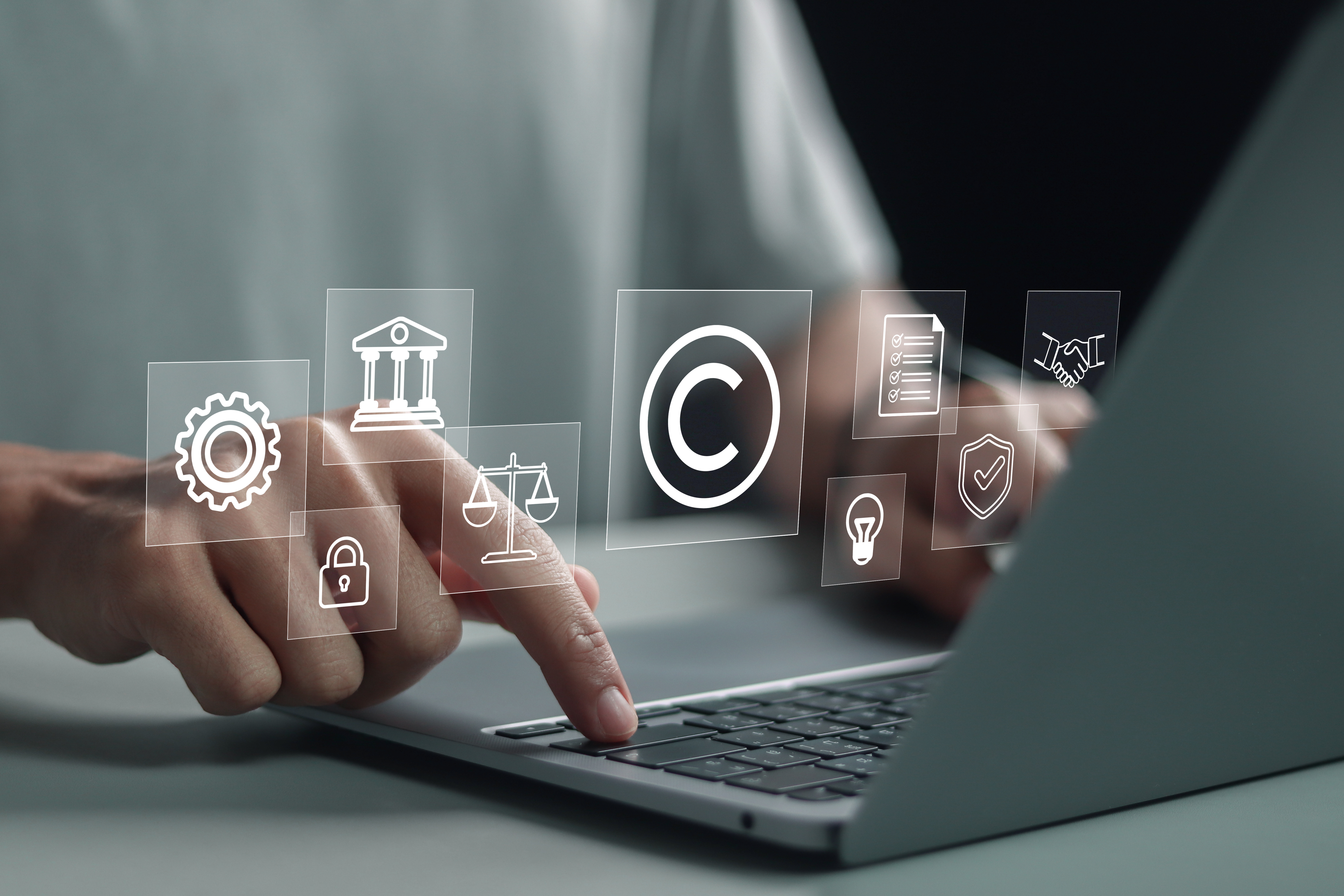 Person using laptop with copyright icon for author rights and patent intellectual property. Patented patent copyright law business technology concept.
